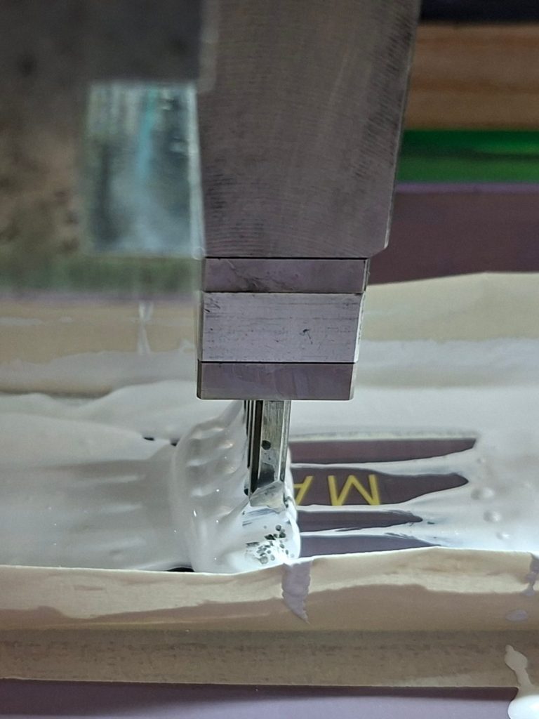 Bedruckung eines ovalen Flakons mit einem Schriftzug in Weiß